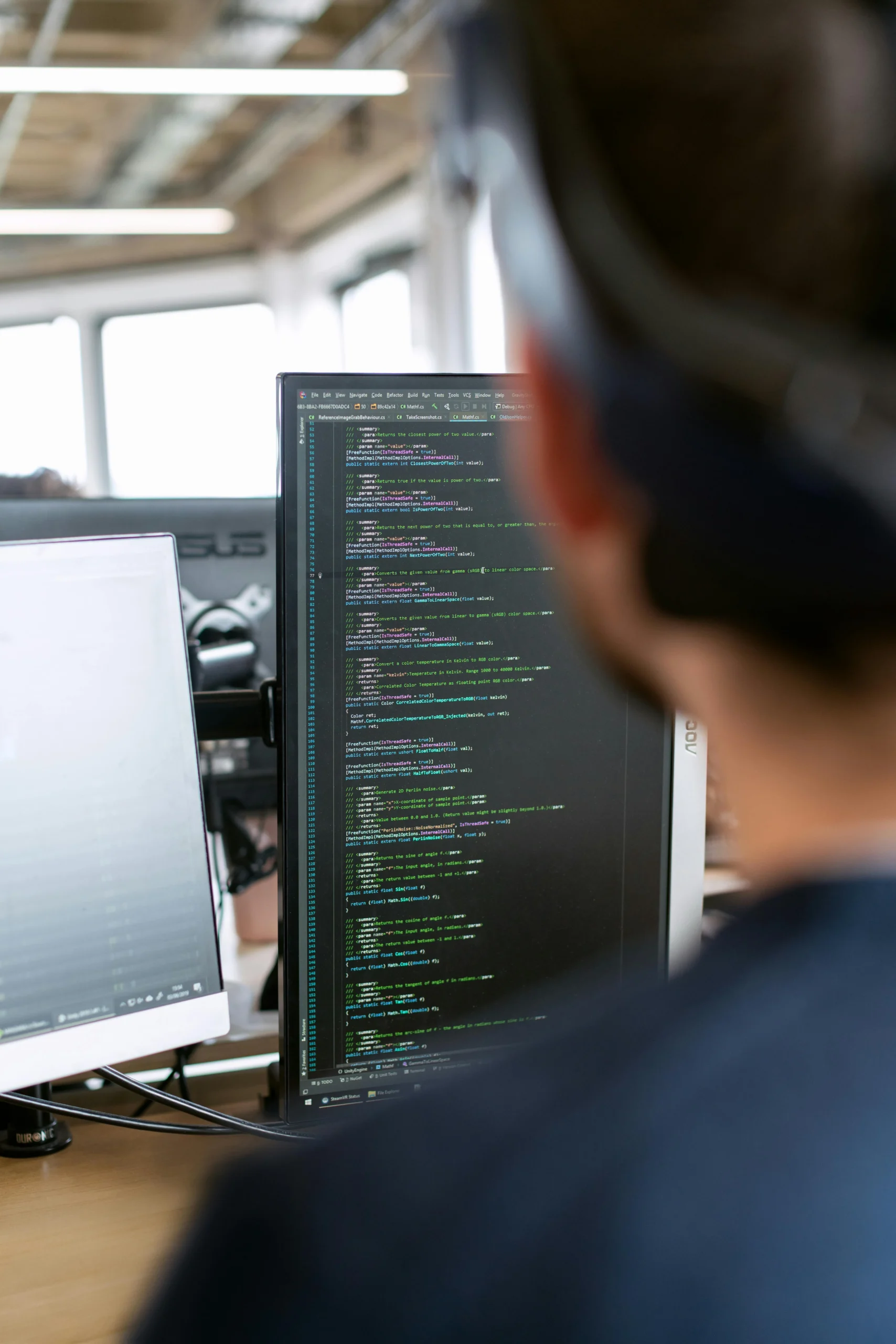Afbeelding van een persoon achter een beeldscherm waarop code te zien is